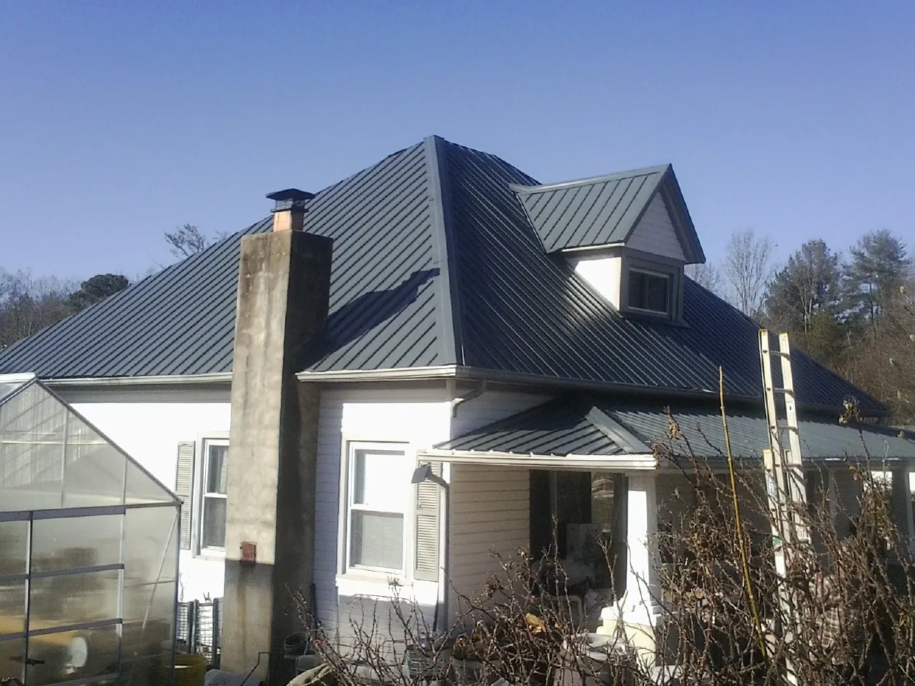 Dark blue standing seam metal roof on a white farmhouse with dormer — Slate & Tile Roof Repair by Roofing Brothers in Rockvale