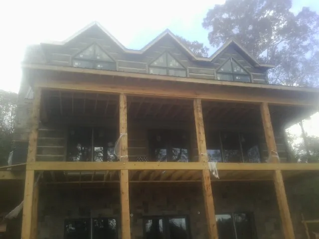 Dormers and porch framing on a large log home under construction — Roof Coating work by our crew in Rockvale