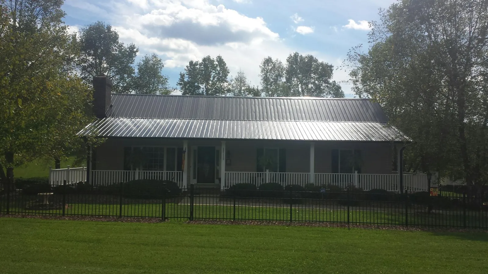 Gray metal roof on a brick ranch with a full width front porch — Gutter Guard Installation work by our crew in Rockvale