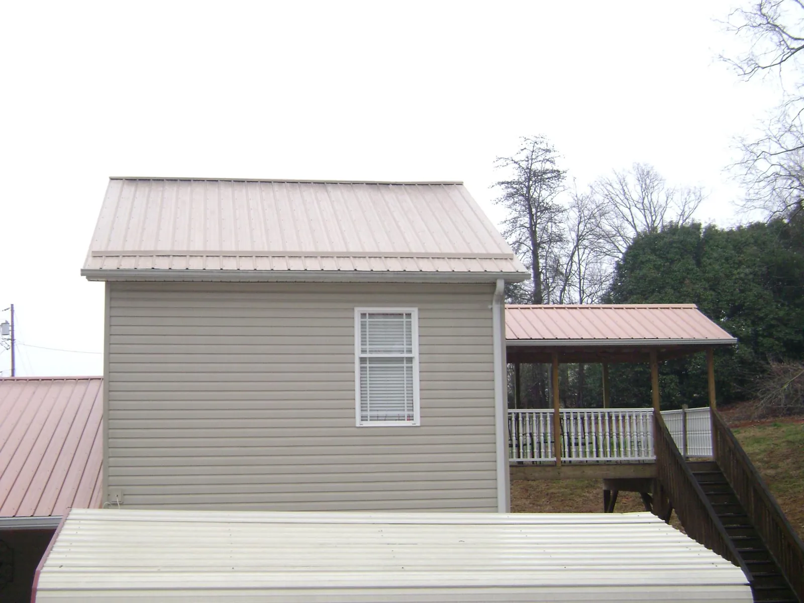 Tan metal roofs on a two story addition and attached porch, from a Roof Replacement job in Rockvale