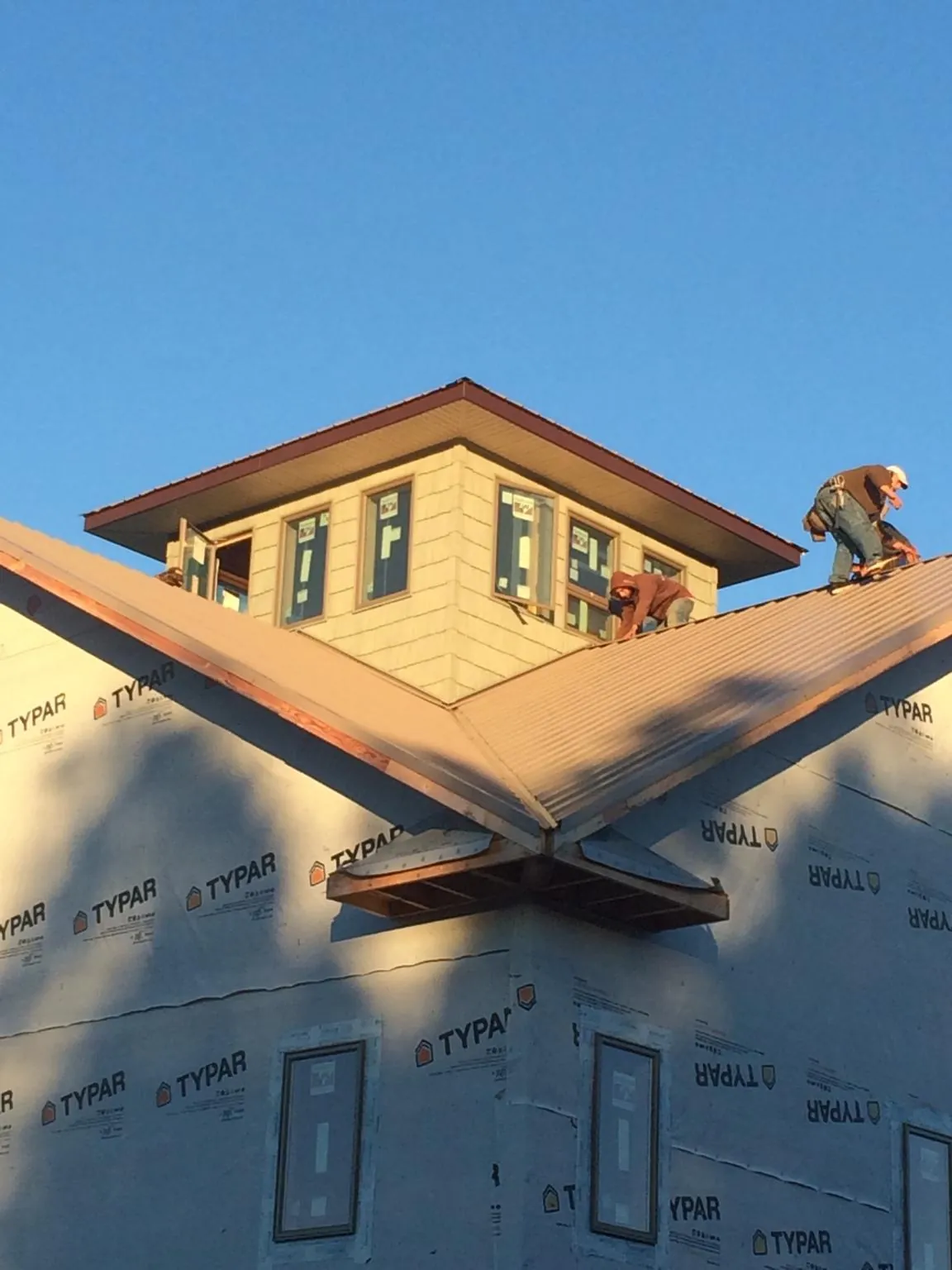 Roofers working around a rooftop cupola on a new metal roof at sunset — Roof Waterproofing in Rockvale by Roofing Brothers